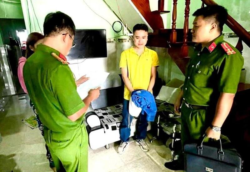 Cơ quan Cảnh sát điều tra Công an Bình Thuận đọc Quyết định khởi tố bị can, bắt tạm giam Nguyễn Quốc Đạt (đứng giữa, áo vàng). (Ảnh: Công an cung cấp)