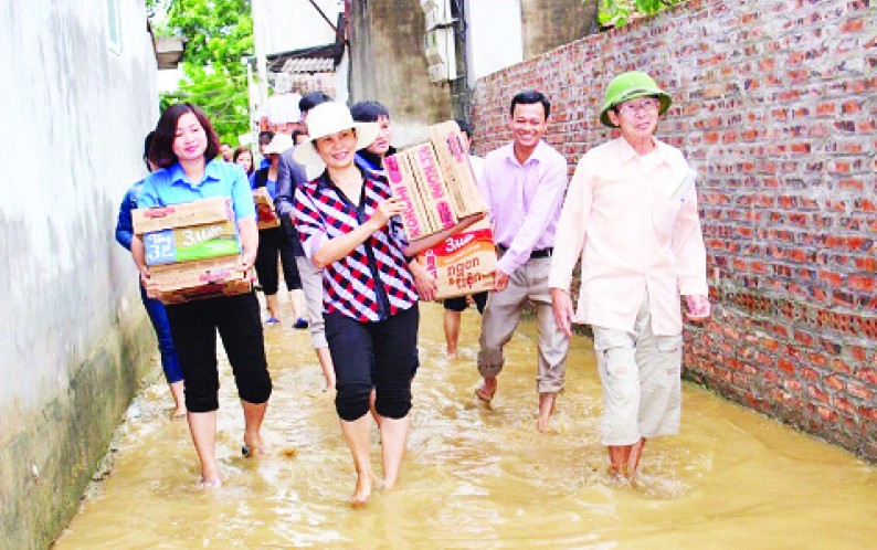 Chị Bùi Thị Tú Oanh (người đi đầu) trong một chuyến công tác hỗ trợ người dân bị lũ lụt tại huyện Chương Mỹ năm 2017 .