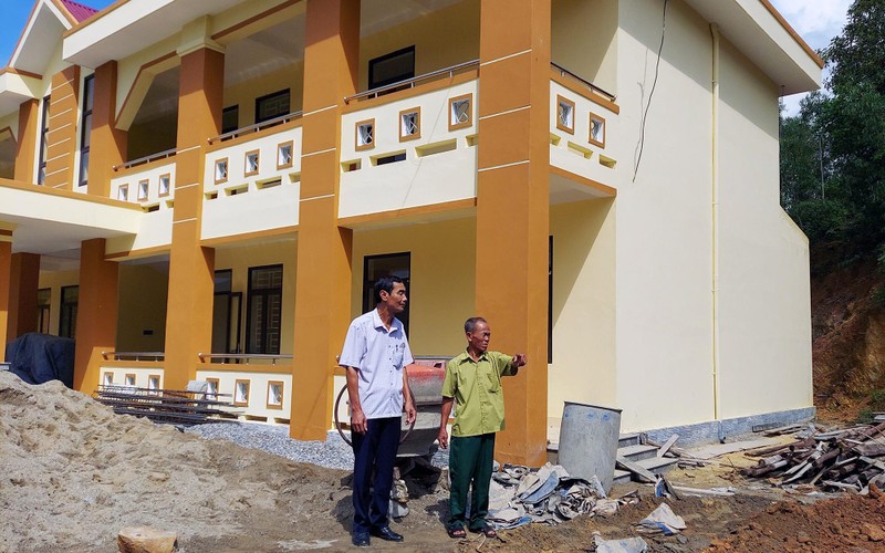 Già làng Hồ Văn Hơn (bên phải) bên ngôi trường mới được xây dựng trên phần đất già hiến tặng. 