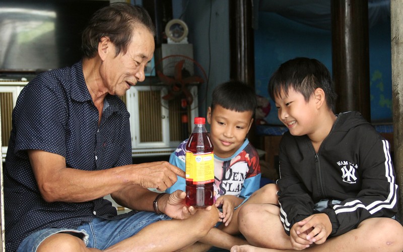 Nghệ nhân Trần Ngọc Vinh và các cháu bên sản phẩm nước mắm của gia đình. 