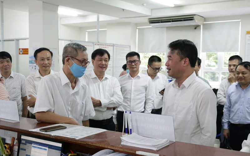 Lãnh đạo Bảo hiểm xã hội Việt Nam trao đổi với người dân đến làm thủ tục tại Bộ phận một cửa của Bảo hiểm xã hội Thành phố Hồ Chí Minh. (Ảnh TÂM TRUNG) 