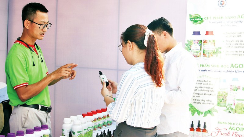 Anh Lê Việt Trung (ngoài cùng, bên trái) giới thiệu về sản phẩm của mình cho khách hàng. 