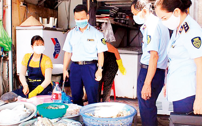 Lực lượng Quản lý thị trường kiểm tra vệ sinh an toàn thực phẩm tại một chợ dân sinh ở quận Hoàng Mai. (Ảnh Hoài Nam)