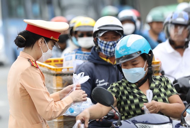 Nữ Cảnh sát giao thông phát nước suối cho người đi xe máy.