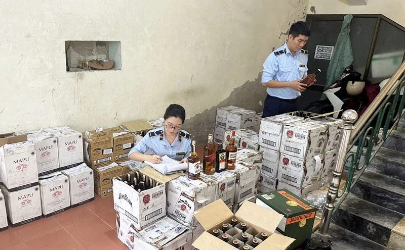 Cán bộ Cục Quản lý thị trường tỉnh Quảng Bình kiểm tra tem nhãn rượu không rõ nguồn gốc bị thu giữ. (Ảnh: Hương Giang)