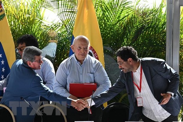 Trưởng đoàn đàm phán ELN Pablo Beltran (trái) và đại diện đoàn đàm phán của Chính phủ Ivan Cepeda (phải) trao đổi văn kiện thỏa thuận đạt được giữa 2 bên tại vòng đàm phán ở Caracas, Venezuela ngày 12/12/2022. (Ảnh: AFP/TTXVN)