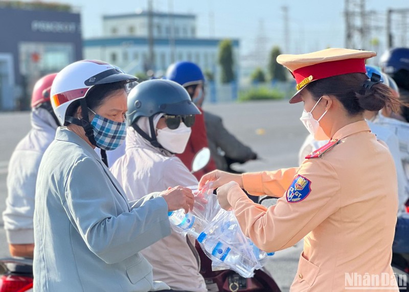 Nữ chiến sĩ Cảnh sát giao thông Công an tỉnh Đồng Nai phát nước suối, khăn lạnh cho người dân.