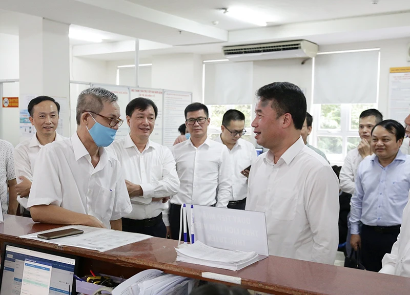 Tổng Giám đốc Bảo hiểm xã hội Việt Nam Nguyễn Thế Mạnh (hàng đầu, bên phải) trao đổi với người dân đến làm việc tại phòng "một cửa" (Bảo hiểm xã hội TP Hồ Chí Minh). (Ảnh TÂM TRUNG)