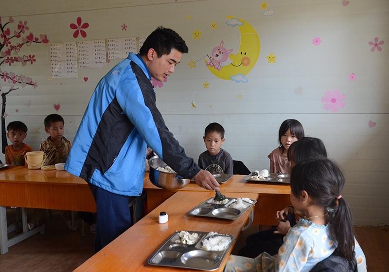 Thầy giáo Lò Văn Bính cẩn thận chia từng phần cơm cho học sinh ở Pú Vang.