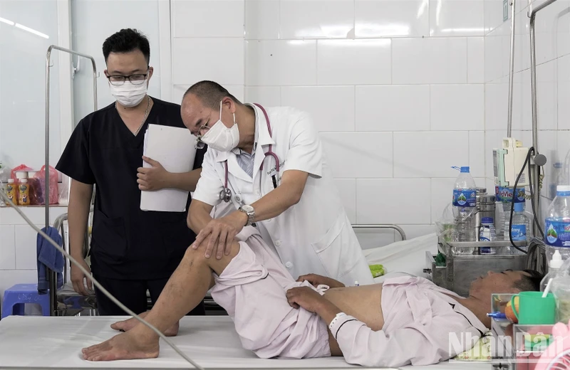 Tiến sĩ, bác sĩ Đỗ Duy Cường, Giám đốc Trung tâm Bệnh Nhiệt đới, Bệnh viện Bạch Mai khám cho người bệnh sốt xuất huyết. (Ảnh: THẾ KHẢI)