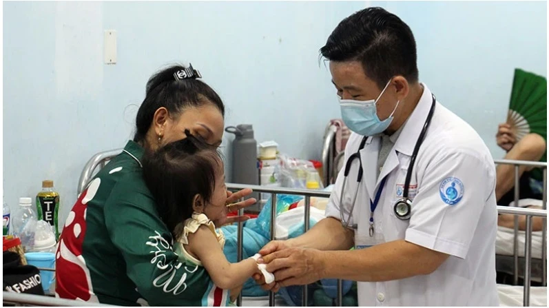 Bác sĩ Bệnh viện Nhi đồng 1 TP Hồ Chí Minh thăm khám cho trẻ mắc tay chân miệng. (Ảnh: THẾ ANH)