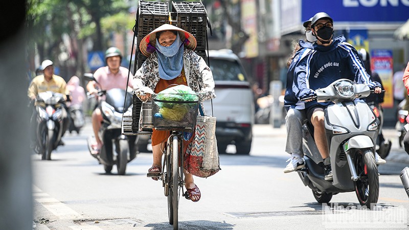 Dưới ánh nắng gay gắt, kèm nhiệt độ cao, nhiều người lao động ở Hà Nội phải trùm kín người khi di chuyển ngoài trời. Ảnh: THÀNH ĐẠT