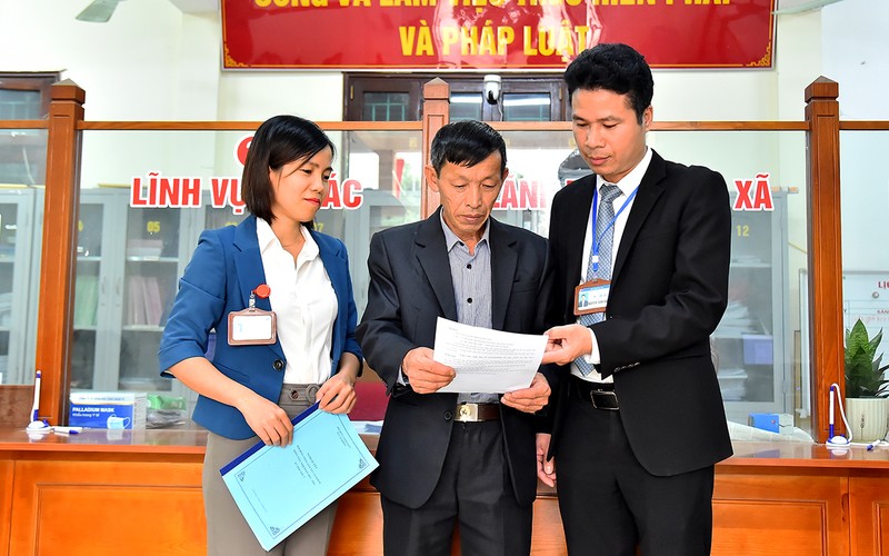 Chủ tịch Ủy ban nhân dân xã Cần Kiệm (huyện Thạch Thất, Hà Nội) Nguyễn Tuấn Chinh (bên phải) trao đổi công việc với cán bộ Ủy ban nhân dân xã. (Ảnh MỸ HÀ)
