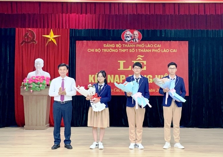 Lãnh đạo Thành ủy Lào Cai tặng hoa chúc mừng 3 đảng viên mới là học sinh Trường Trung học phổ thông số 1 thành phố Lào Cai. (Ảnh: NGUYỄN NHIN) 
