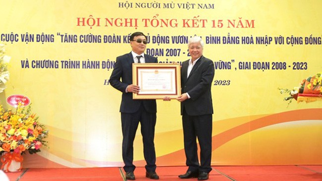 Đồng chí Đỗ Văn Chiến trao Huân chương Lao động hạng Ba tặng ông Phạm Xuân Trường, Ủy viên Ban Thường vụ Hội Người mù Việt Nam, với những đóng góp vì người mù. (Ảnh: mattran.org.vn)