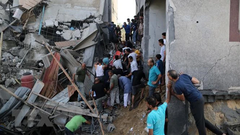 Người dân tìm kiếm người bị mắc kẹt trong những đống đổ nát sau vụ không kích của Israel tại Khan Younis, Dải Gaza, ngày 11/10/2023. (Ảnh: THX/TTXVN)