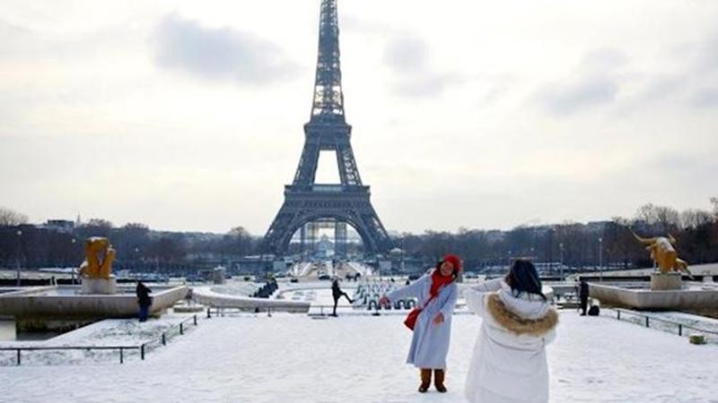 Khách du lịch chụp ảnh lưu niệm dưới chân tháp Eiffel. (Nguồn: TTXVN)