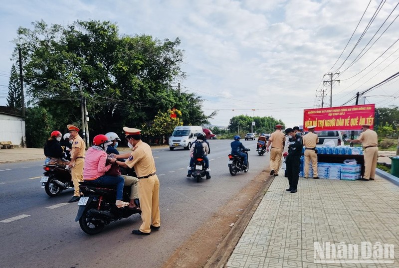 Lực lượng Cảnh sát giao thông Công an tỉnh Đồng Nai phát nước suối， khăn lạnh cho người dân về quê đón Tết trên quốc lộ 20.