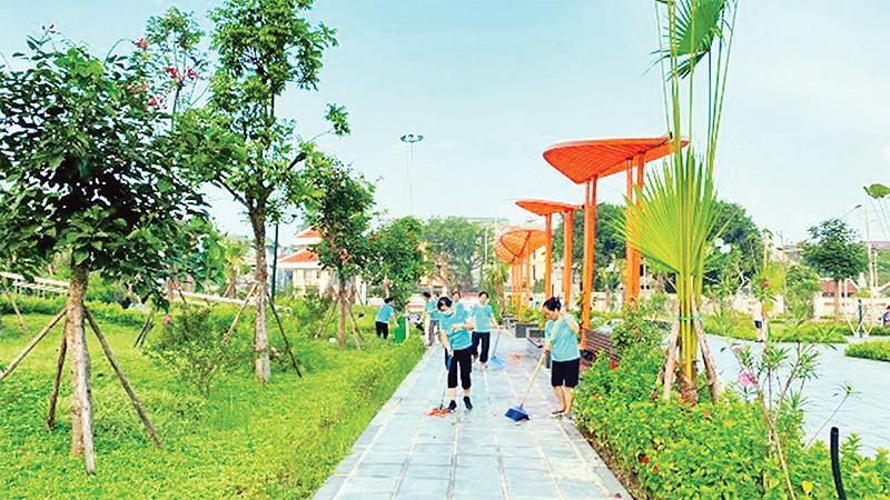 Người dân tham gia vệ sinh môi trường tại vườn hoa Kim Quan, phường Việt Hưng, quận Long Biên. (Ảnh VĂN MẠNH) 