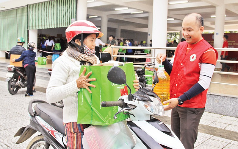 Hội viên Hội Chữ thập đỏ hỗ trợ người dân mua hàng ở Chợ Tết Nhân ái tại Ðà Nẵng. (Ảnh THANH TÂM) 