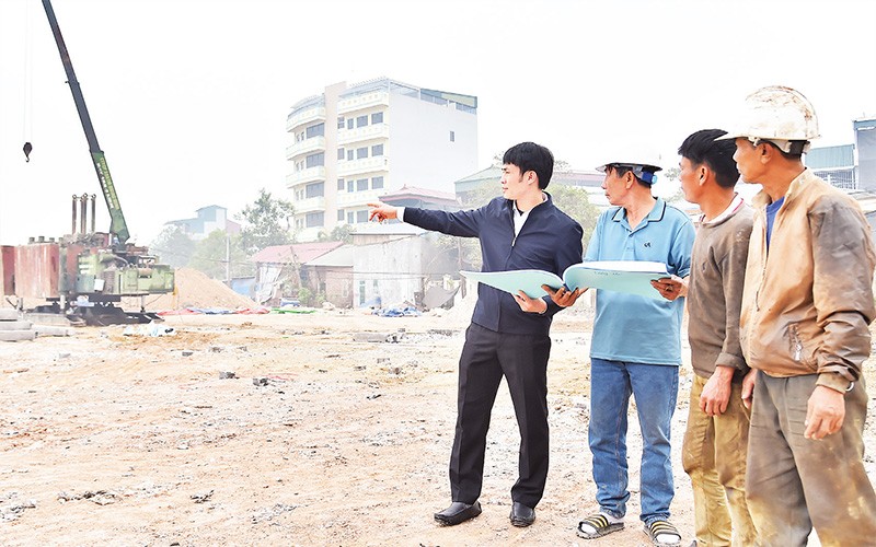 Chủ tịch Ủy ban nhân dân xã Chàng Sơn Nguyễn Trần Vượng (ngoài cùng bên trái) trao đổi với công nhân xây dựng về dự án trường mầm non mới của xã. 