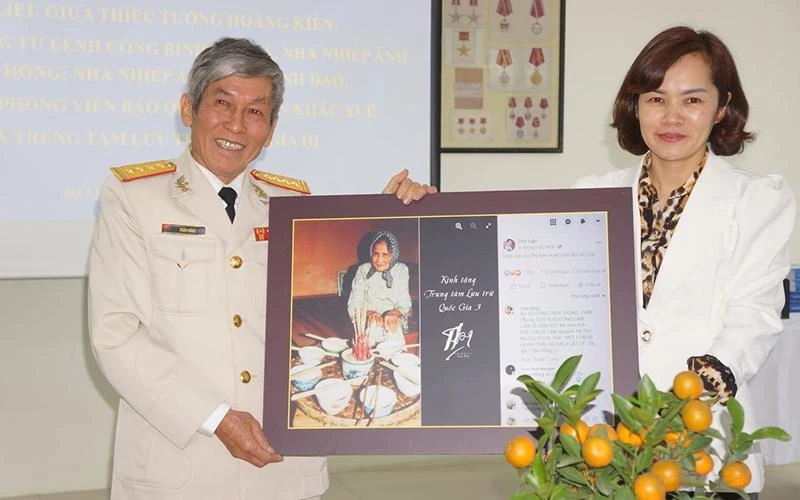 Đại tá, nghệ sĩ nhiếp ảnh Trần Hồng trao bộ ảnh chân dung Mẹ Việt Nam tặng đại diện Trung tâm Lưu trữ quốc gia 3. (Ảnh do NSNA Trần Hồng cung cấp)