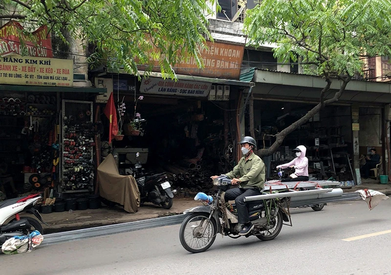 Xe máy cũ, nát chở hàng cồng kềnh trên phố Đê La Thành (Hà Nội). (Ảnh HỮU NGHỊ)