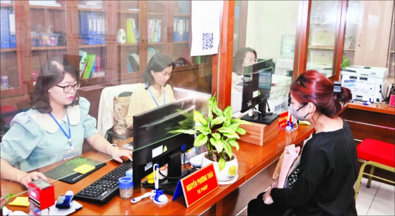 Công chức tại Bộ phận một cửa UBND phường Hàng Bài giải quyết thủ tục hành chính cho người dân. (Ảnh Duy Linh)