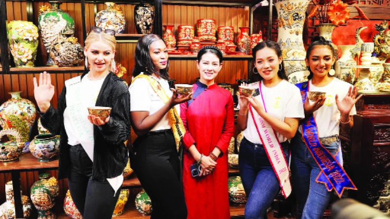 Nghệ nhân Vũ Như Quỳnh (đứng giữa) giao lưu với khách tham quan là những người đẹp tham gia cuộc thi Hoa hậu Du lịch quốc tế năm 2022 tại một cuộc triển lãm.
