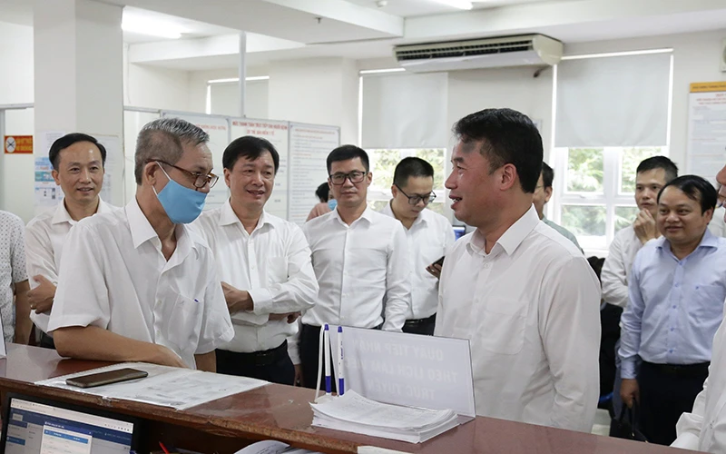 Lãnh đạo Bảo hiểm xã hội Việt Nam trao đổi với người dân đến làm việc tại Bảo hiểm xã hội Thành phố Hồ Chí Minh. (Ảnh TÂM TRUNG)