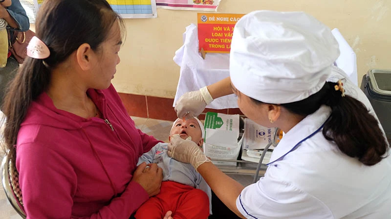 Cán bộ Trạm Y tế xã Đồng Sơn, Hoành Bồ (Quảng Ninh) cho trẻ uống vắc-xin phòng bệnh.
