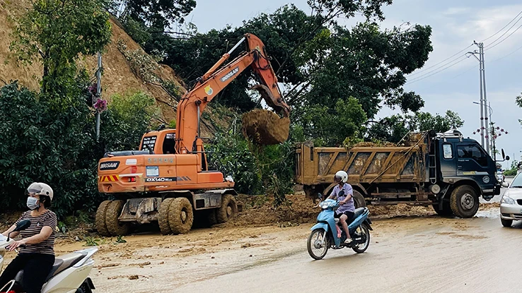 Sử dụng gầu xúc hốt đất, đá do sạt lở núi trên đường Bách Lẫm, thành phố Yên Bái, tỉnh Yên Bái.