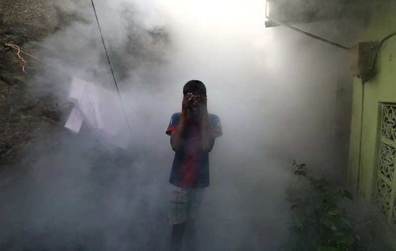 Một cậu bé che mặt để tránh khói khi khi nhân viên y tế hun khói đuổi muỗi phòng sốt xuất huyết tại một khu dân cư ở Colombo, Sri Lanka, ngày 12/7/2023. (Ảnh: Reuters)