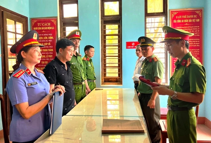 Nguyễn Quốc Trung, Giám đốc Công ty TNHH Thạch Phú Hưng (áo đen, thứ 2 từ trái sang) nghe đọc lệnh khởi tố. (Ảnh: Công an cung cấp)