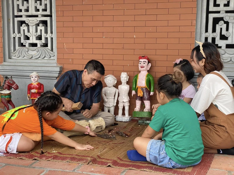 Nghệ nhân phường rối nước Đào Thục giới thiệu với khách du lịch về nghệ thuật tạo hình quân rối.