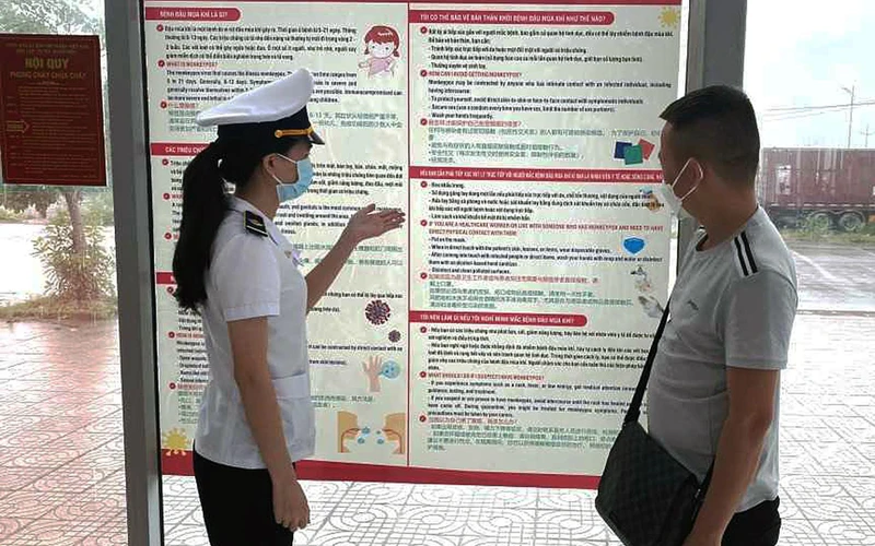 Kiểm dịch viên của Trung tâm Kiểm dịch y tế quốc tế Quảng Ninh tuyên truyền về bệnh đậu mùa khỉ tại Cửa khẩu Bắc Luân II (TP Móng Cái) cho các chủ xe. (Ảnh NGUYỄN HOA) 