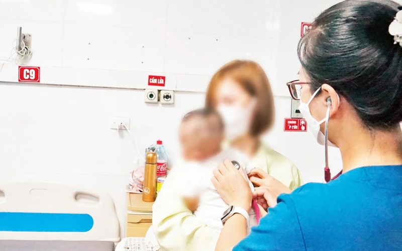 Bác sĩ tại Bệnh viện Thanh Nhàn khám bệnh cho một trẻ bị suy hô hấp. (Ảnh Trà My) 