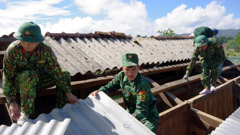 Cán bộ, nhân viên Ðoàn 92 giúp đỡ gia đình chị Pu Riu Thị Ngách lợp lại ngôi nhà mới. 