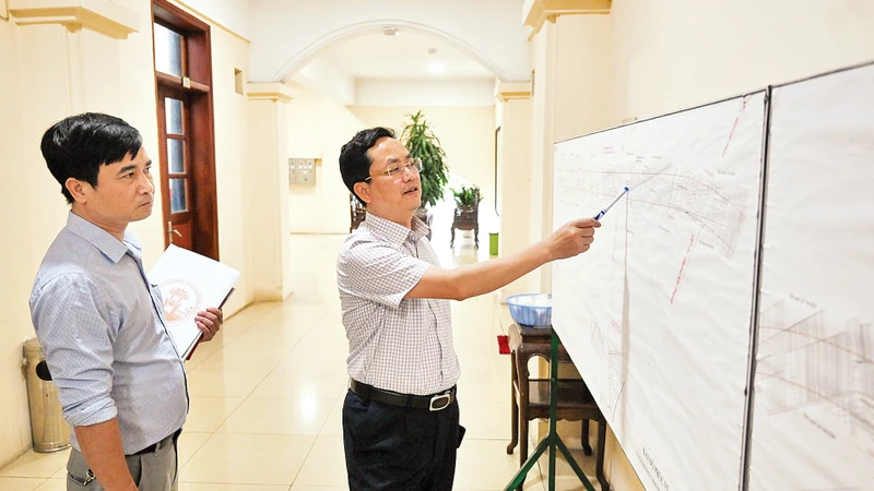Cán bộ Trung tâm Phát triển quỹ đất huyện Mê Linh rà soát bản đồ dự án xây dựng hạ tầng khu vực tái định cư đường Vành đai 4 - vùng Thủ đô. (Ảnh MINH HÀ) 
