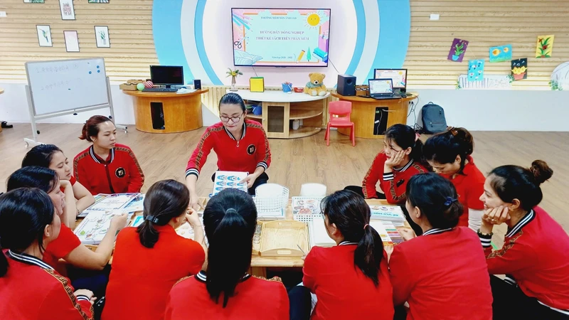 Cô giáo Ðào Thị Nhung chia sẻ với đồng nghiệp quy trình làm ra một bộ sách bóc dán. 
