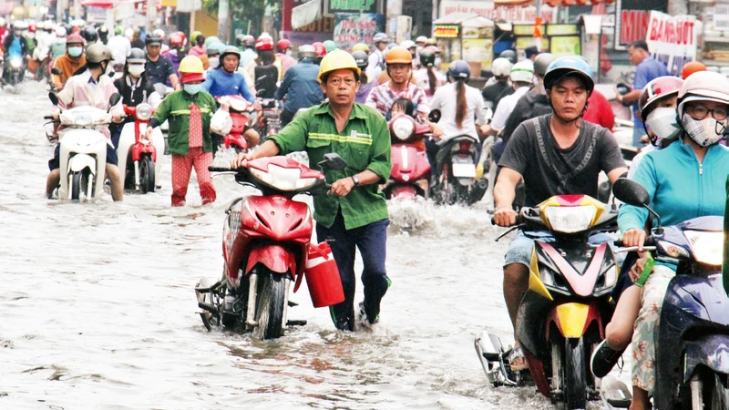 Nước dâng cao do triều cường trên đường Lê Văn Lương, xã Phước Kiển, huyện Nhà Bè khiến việc đi lại của người dân gặp khó khăn (Ảnh Anh Thế) 