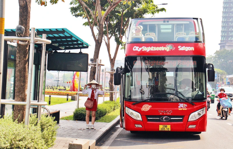 Người dân đón xe buýt tại trạm Bến Bạch Đằng, đường Tôn Đức Thắng, Quận 1. (Ảnh THẾ ANH) 
