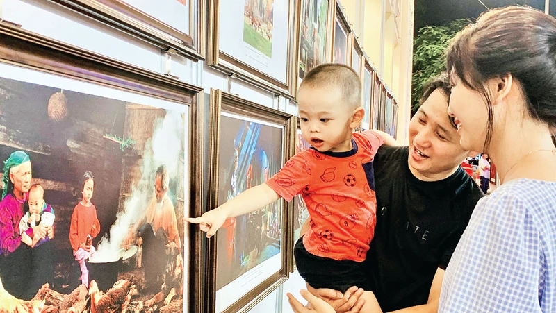 Gia đình trẻ tham quan trưng bày ảnh “Nét đẹp trong văn hóa các gia đình Việt Nam”.