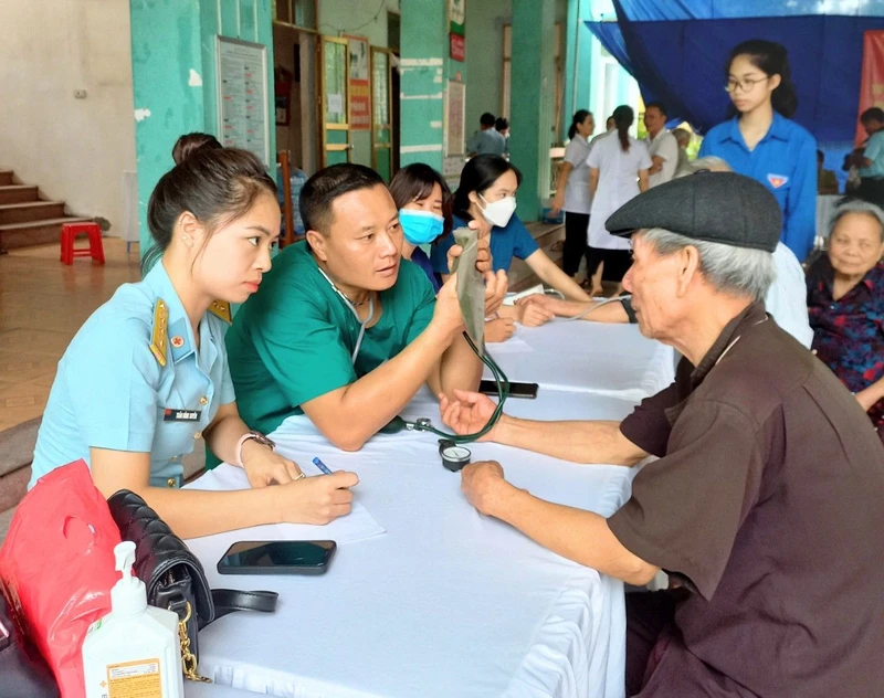 Các y, bác sĩ Trung đoàn 916 (Sư đoàn Không quân 371) đo huyết áp, tư vấn sức khỏe cho đối tượng chính sách đến khám bệnh.