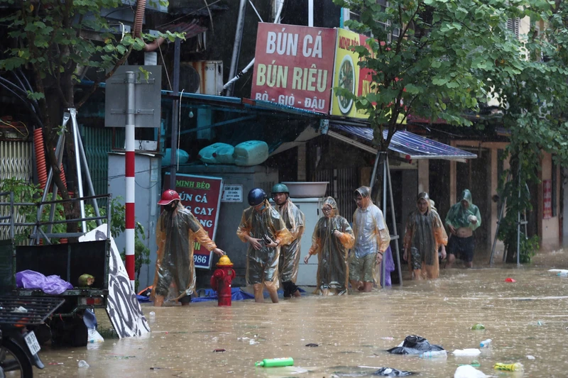 Người dân di chuyển đến nơi an toàn khi nước tại phố Chương Dương Độ (quận Hoàn Kiếm, Hà Nội) dâng cao. (Ảnh THẾ ĐẠI) 