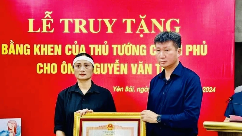 Chủ tịch Ủy ban nhân dân tỉnh Yên Bái Trần Huy Tuấn trao Bằng khen của Thủ tướng Chính phủ cho gia đình anh Nguyễn Văn Thi. (Ảnh: THANH SƠN)