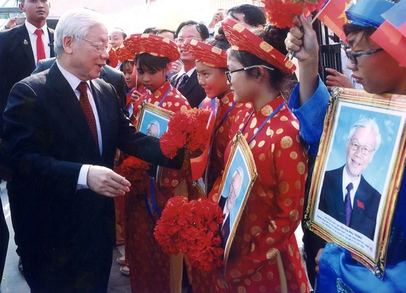 Tổng Bí thư Nguyễn Phú Trọng hỏi thăm các cháu thiếu nhi là con em người gốc Việt Nam tại Campuchia. (Ảnh: Hội Khmer-Việt Nam cung cấp)