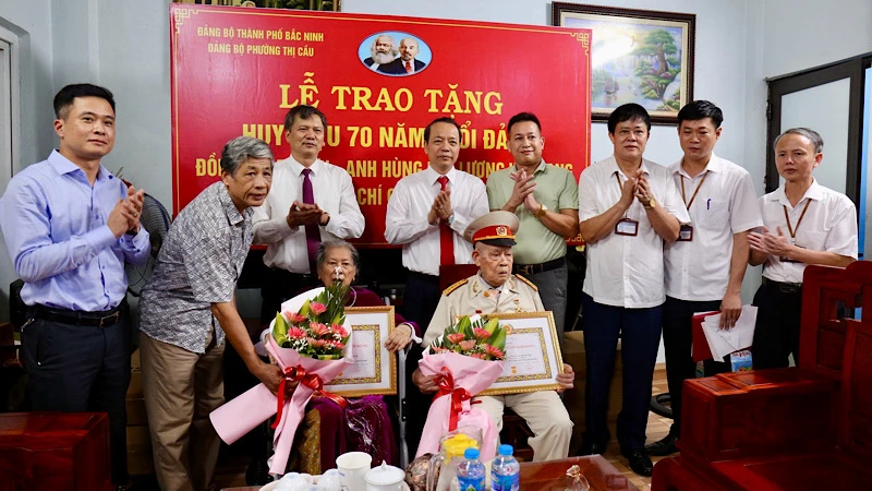 Đồng chí Nguyễn Quốc Chung, Phó Bí thư Thường trực Tỉnh ủy (thứ tư hàng sau từ trái qua) trao Huy hiệu 70 năm tuổi Đảng tặng vợ chồng Anh hùng lực lượng vũ trang nhân dân Tạ Lưu.