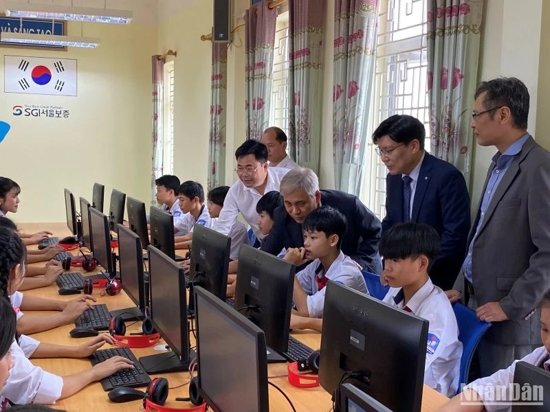 Các đại biểu hướng dẫn các em học sinh sử dụng máy tính mới.