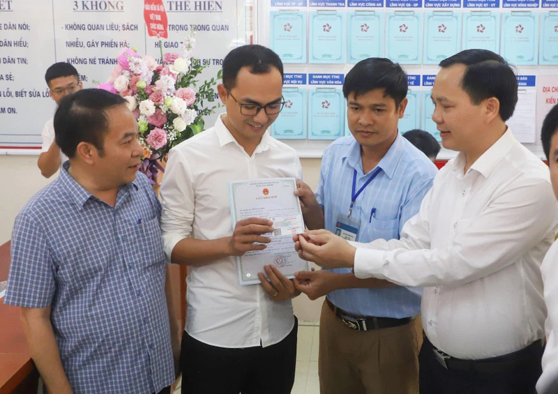 Phó Tổng Giám đốc Chu Mạnh Sinh trao thẻ bảo hiểm y tế của bé gái Đinh Bảo N. cho anh Đinh Tiến Hoàng.